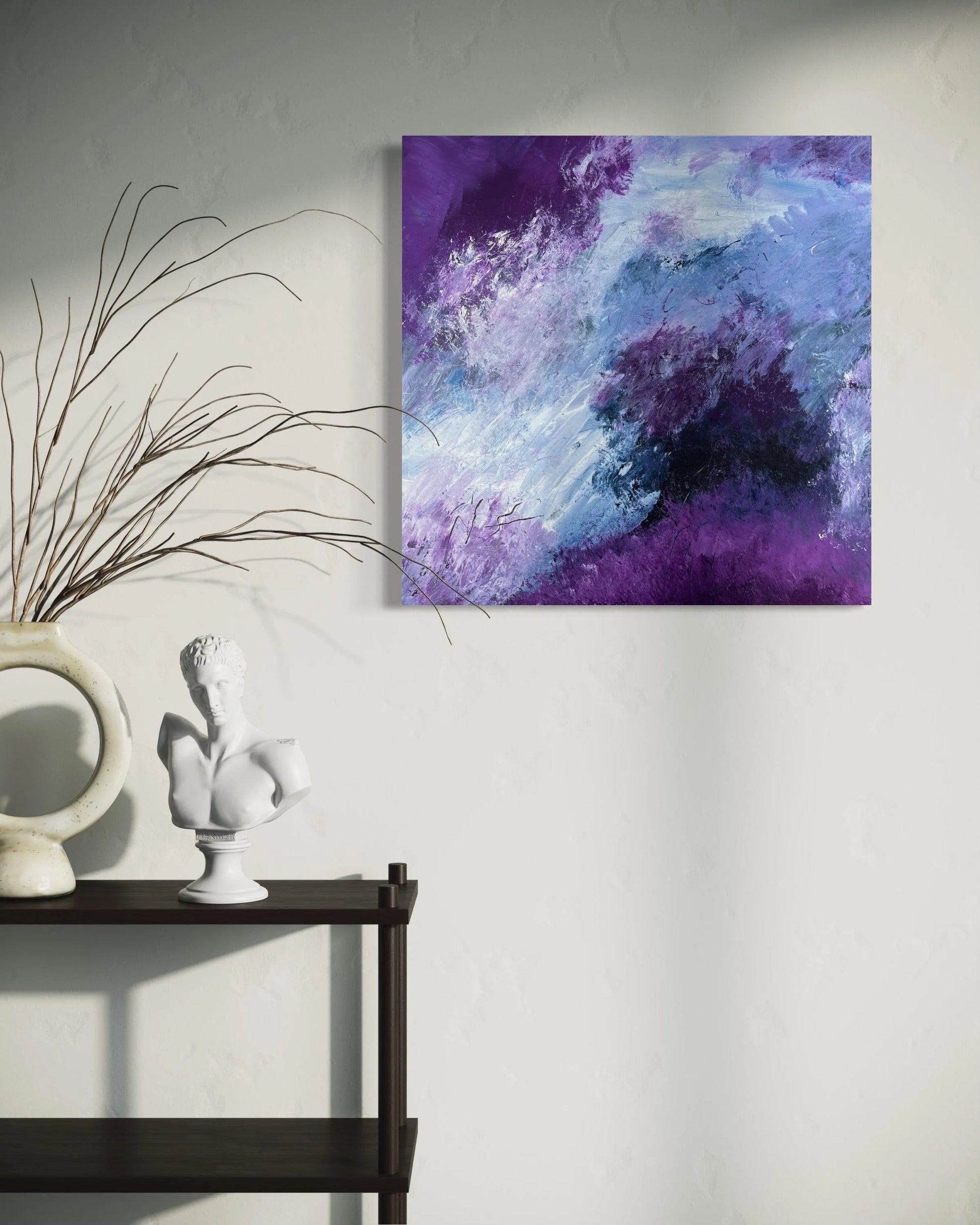 A low shelving unit holing a bust and an unsual round vase with grasses. On the wall to the right and slightly above is a purple abstract painting 'Definitely Maybe'